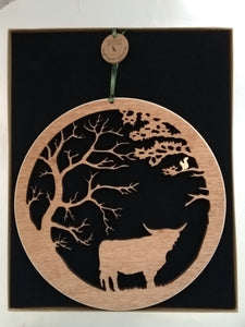 Wooden wall hanging of a highland cow under two trees and a squirrel in the branches